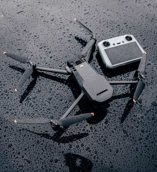 Dron DJI Mavic 3 y su mando mojados por la lluvia, sobre una superficie oscura mojada